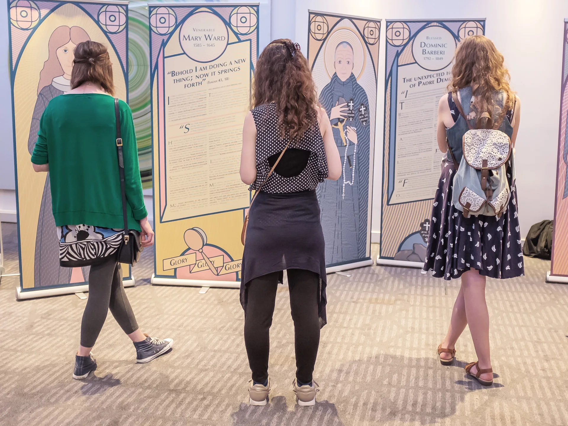 Visitors gathered among the illustrated Holy Unexpected exhibition panels