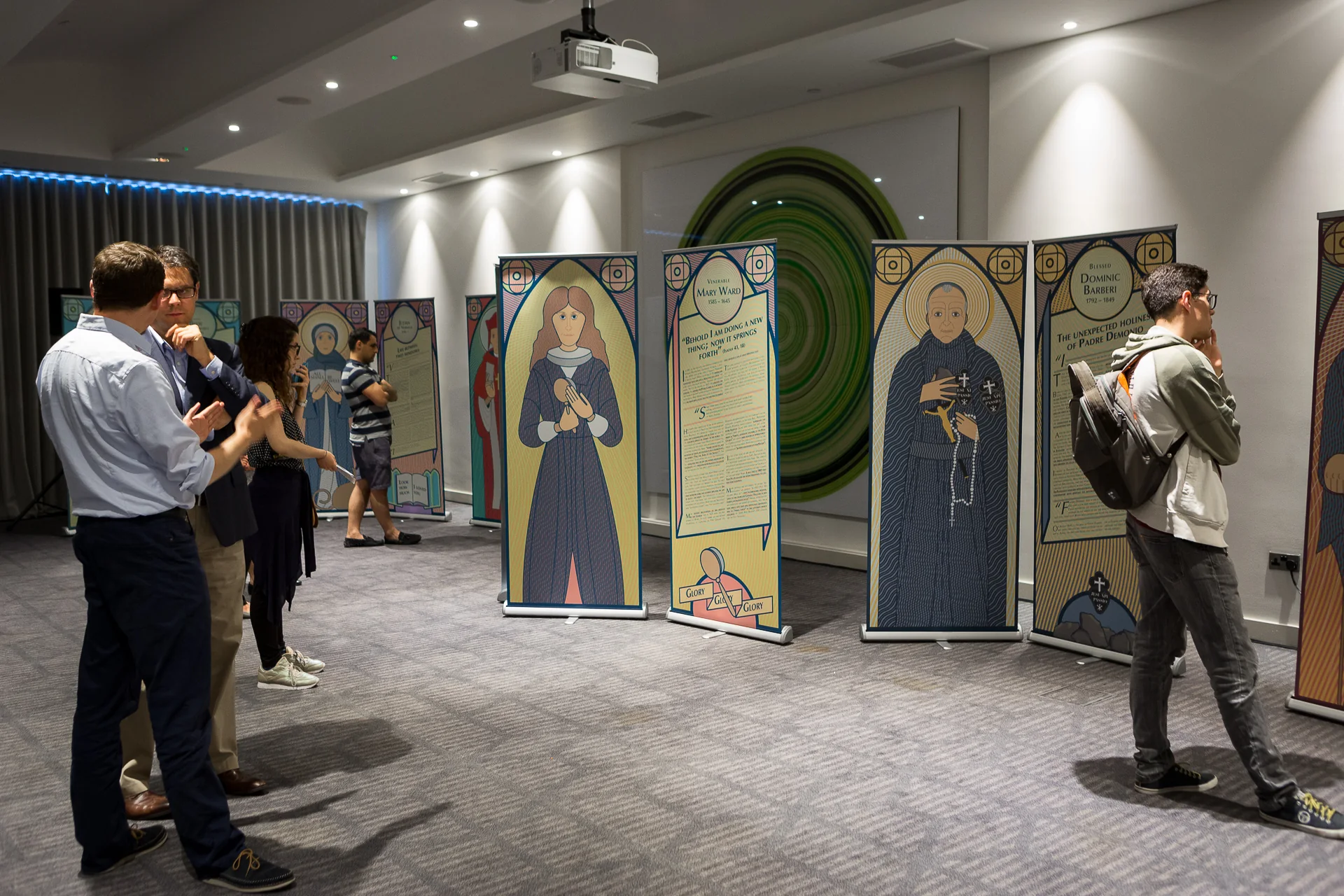Visitors moving among the freestanding illustrated panels at the Holy Unexpected exhibition
